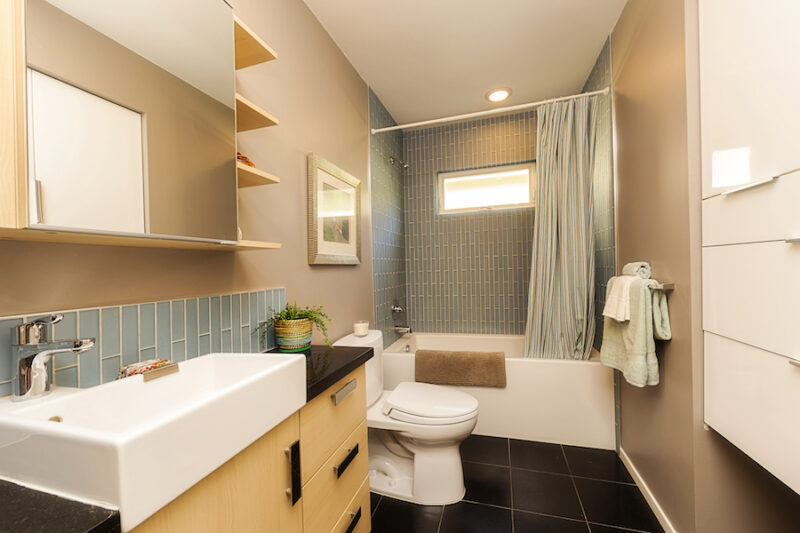 basement bathroom with narrow cabinets, open shelves