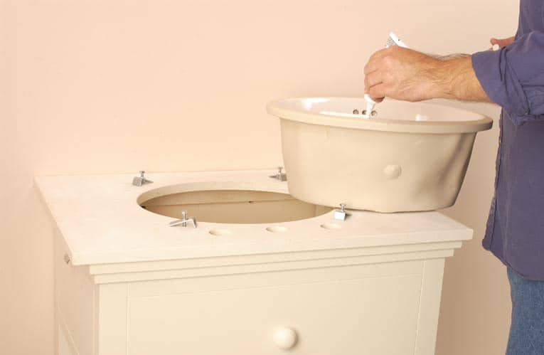 Man applying caulk to edge of a new sink bowl.