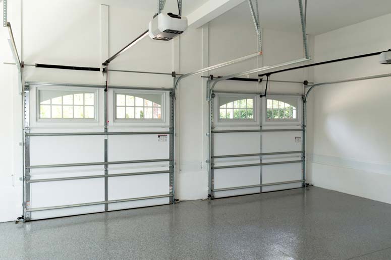 Inside a white garage room with arch stockton windows including overhead torsion springs and electric operators on two garage doors.